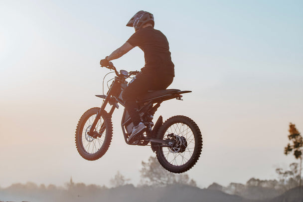 GT73 electric dirt bike rear-view jump at hazy sunset - High performance E-bike