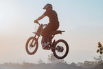 GT73 electric dirt bike rear-view jump at hazy sunset - High performance E-bike