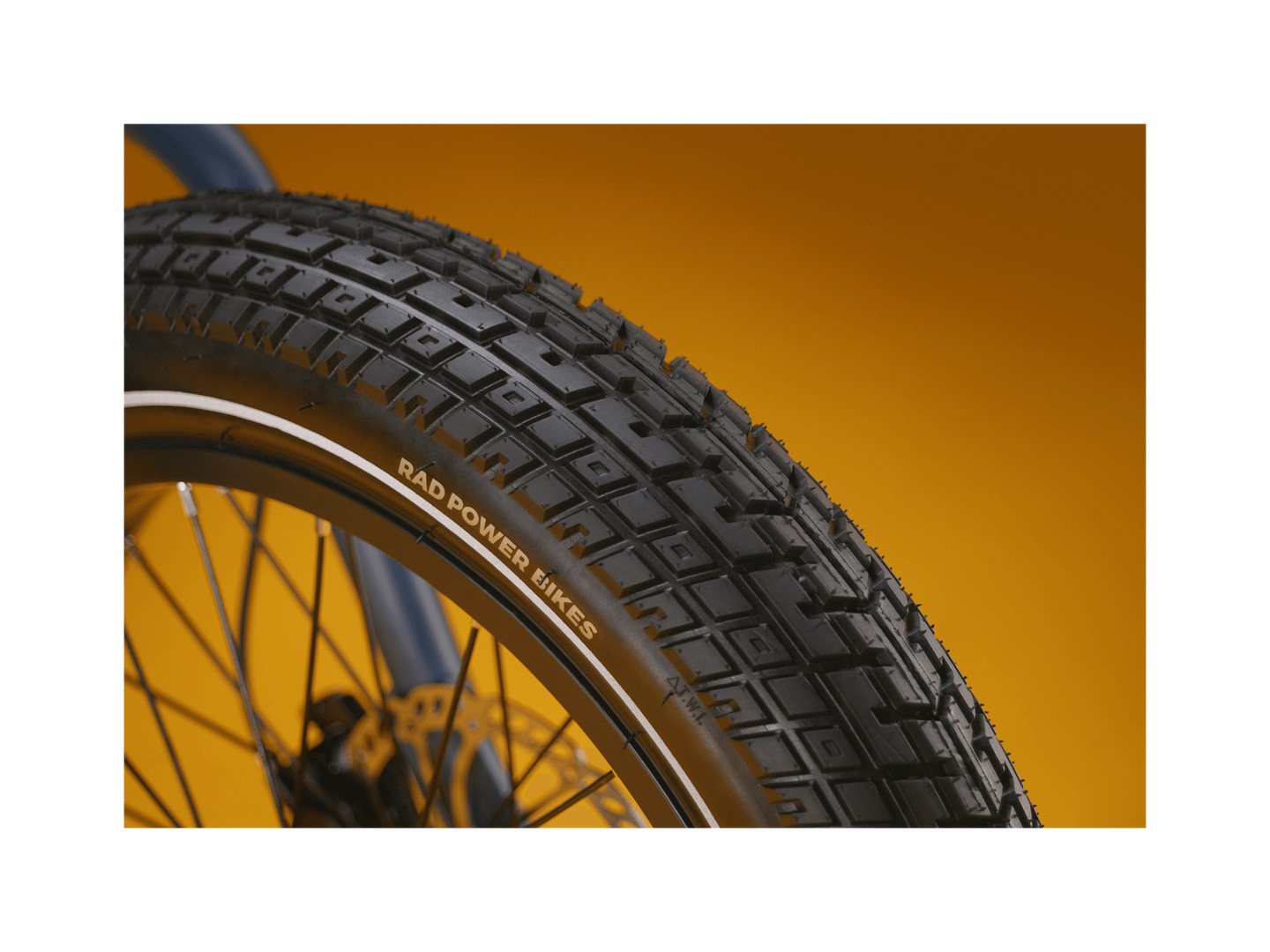 Close up of an ebike tire tread pattern against a gold background.